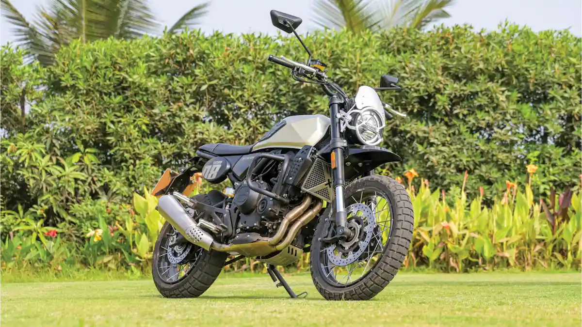 एक एडवेंचर बाइकर पहाड़ों में Brixton बाइक के साथ खड़ा है और नज़ारा देख रहा है।